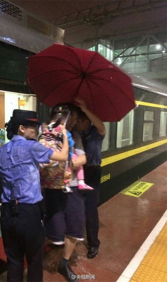 乘务员雨中撑伞护送旅客 浑身湿透