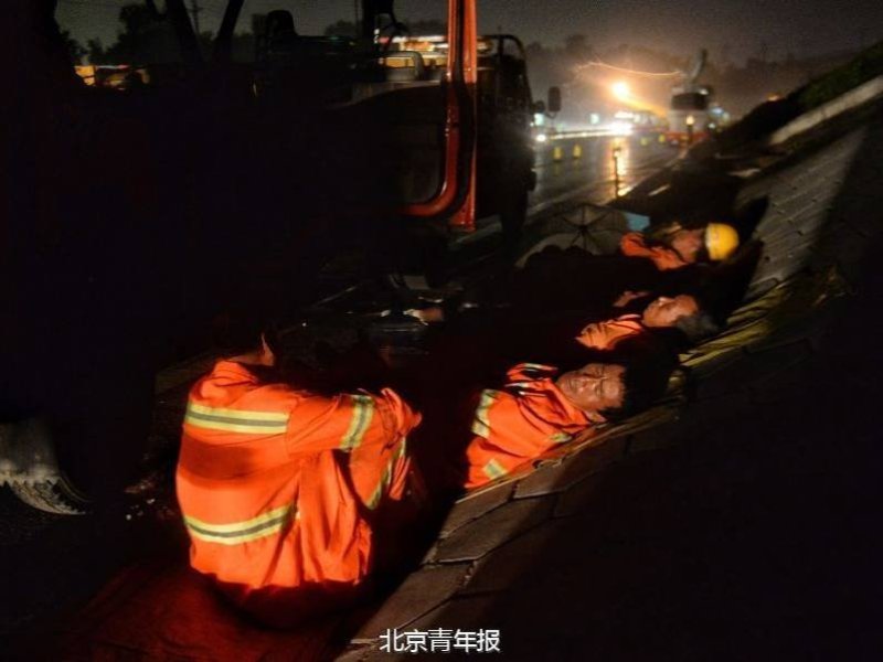 北京大雨夜 上千养路工人通宵执勤睡路边