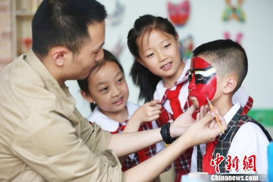 图为学生围观学习画脸谱。　牟健 摄