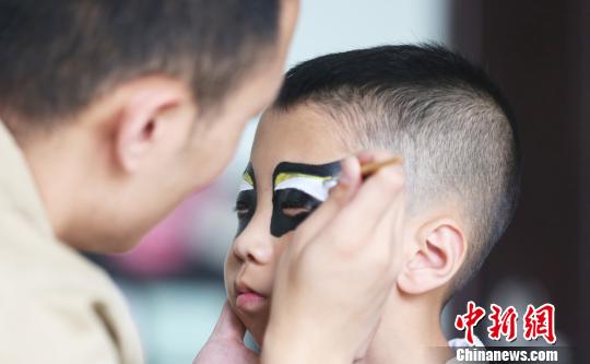 图为专业演员为孩子们画脸谱。　牟健 摄