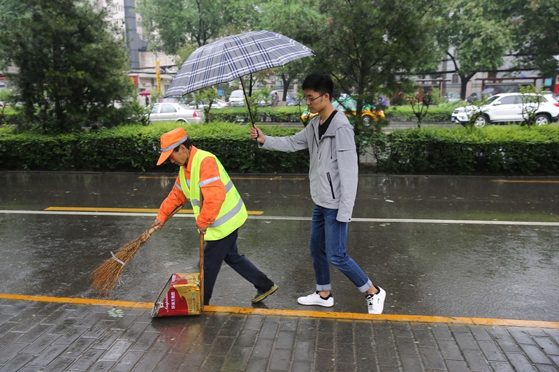 六旬保洁员冒雨清扫 西安大学生为其撑伞40分钟