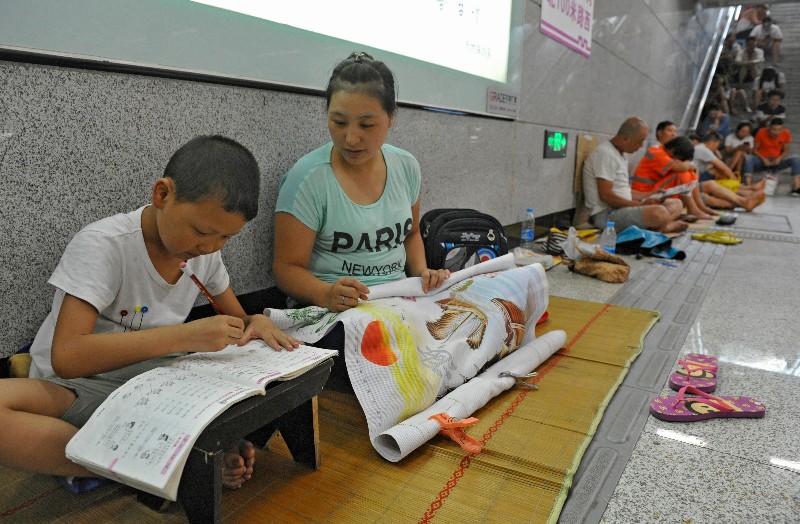 西安地铁站纳凉市民多 孩子趴小凳学习