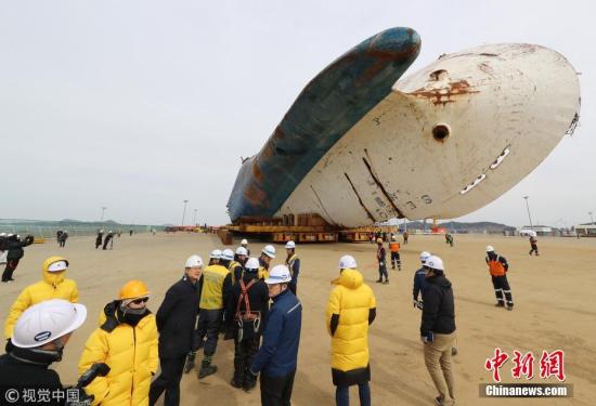 资料图：当地时间2018年2月21日，作业人员在韩国全罗南道木浦新港准备将“世越”号移动至模件运输车（MT）上。当天将“世越”号打横移动后，工作人员准备于5月31日扶正船体。 图片来源：视觉中国