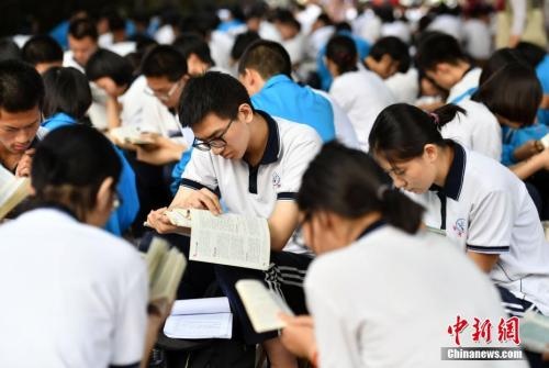 6月7日清晨，河北石家庄一高考点附近，参加高考的学生们利用进入考场前的时间看书复习。 中新社记者 翟羽佳 摄