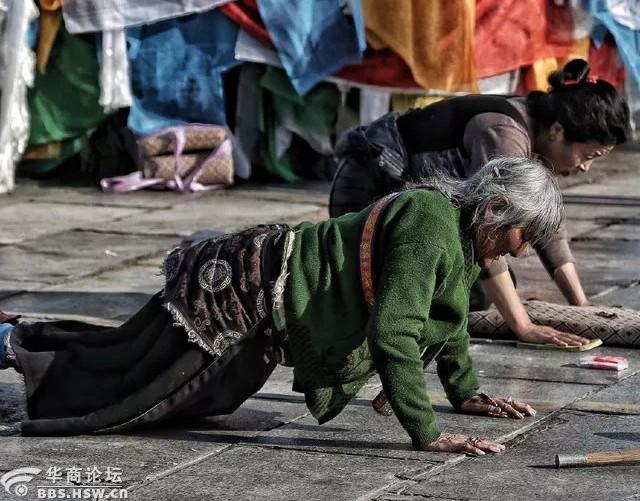 一位老人朝圣的姿势,双手按地用力支撑着自己跪着的身体,头垂下表示对