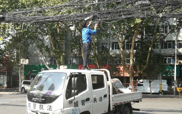 建设西路口一捆线缆垂落阻挡过往车辆 一城管站车顶排险