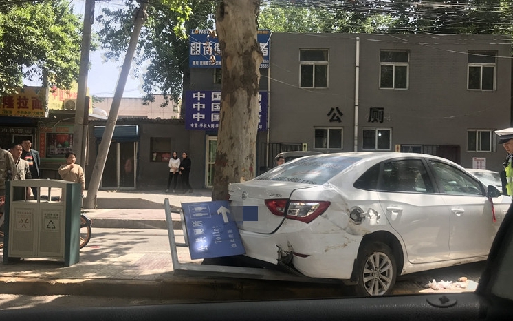 含元路一辆白色轿车冲上人行道 撞倒公共厕所标识
