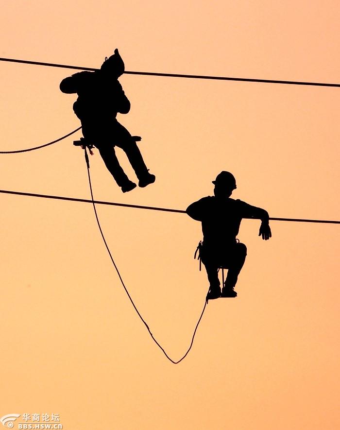 冬日傍晚电力工人在夕阳红中上演空中芭蕾!